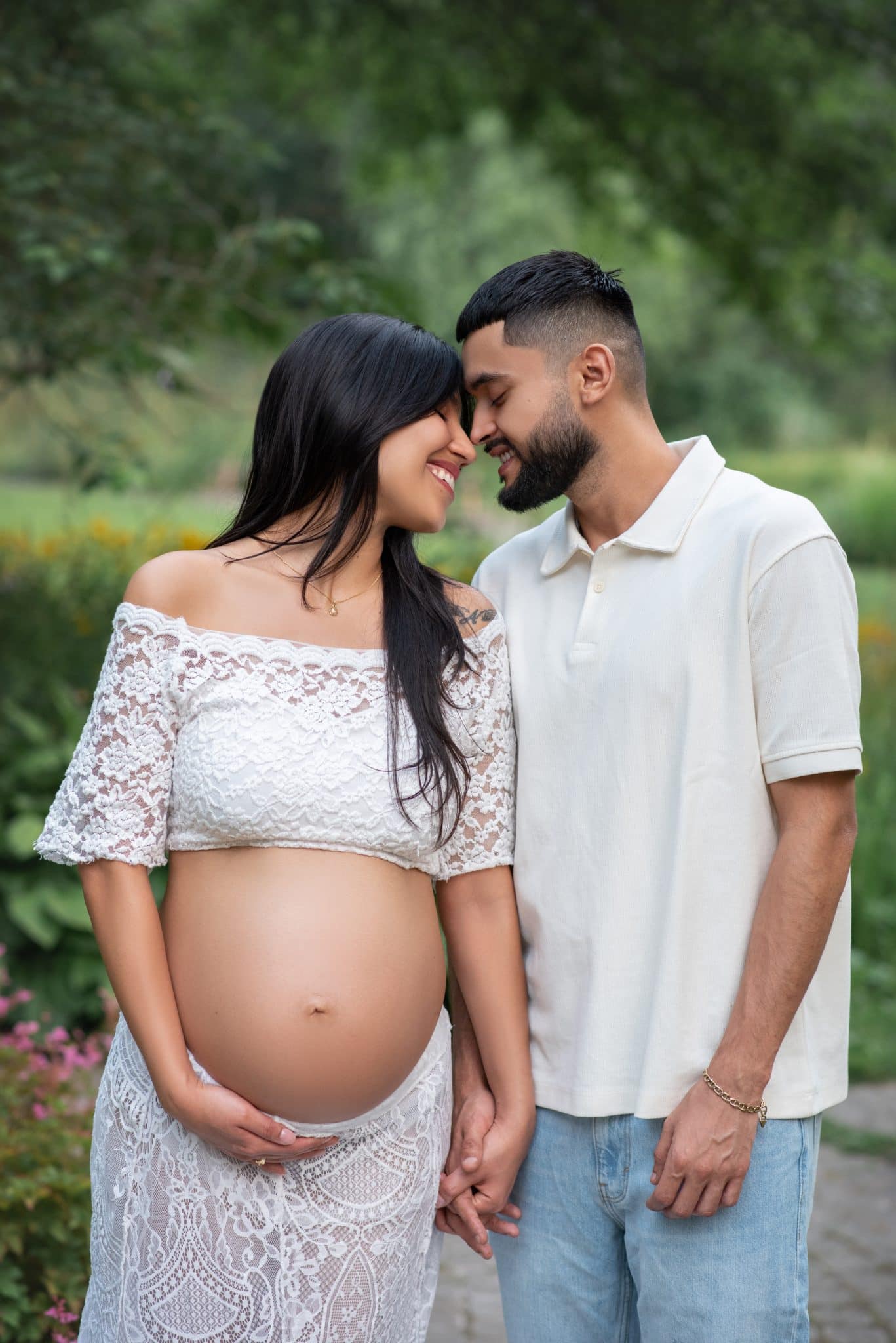 A tender moment between a couple as they lean their heads together in a beautiful park setting for a pregnancy photoshoot Brampton.