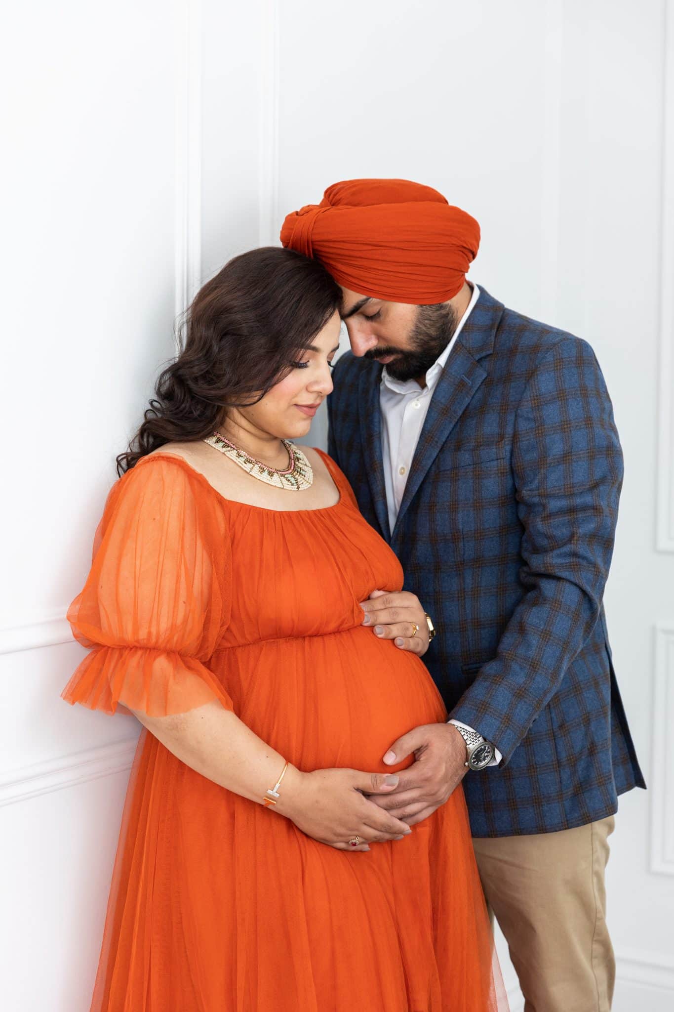 An intimate portrait of a couple in traditional attire sharing a tender moment during their maternity photo session in the GTA.