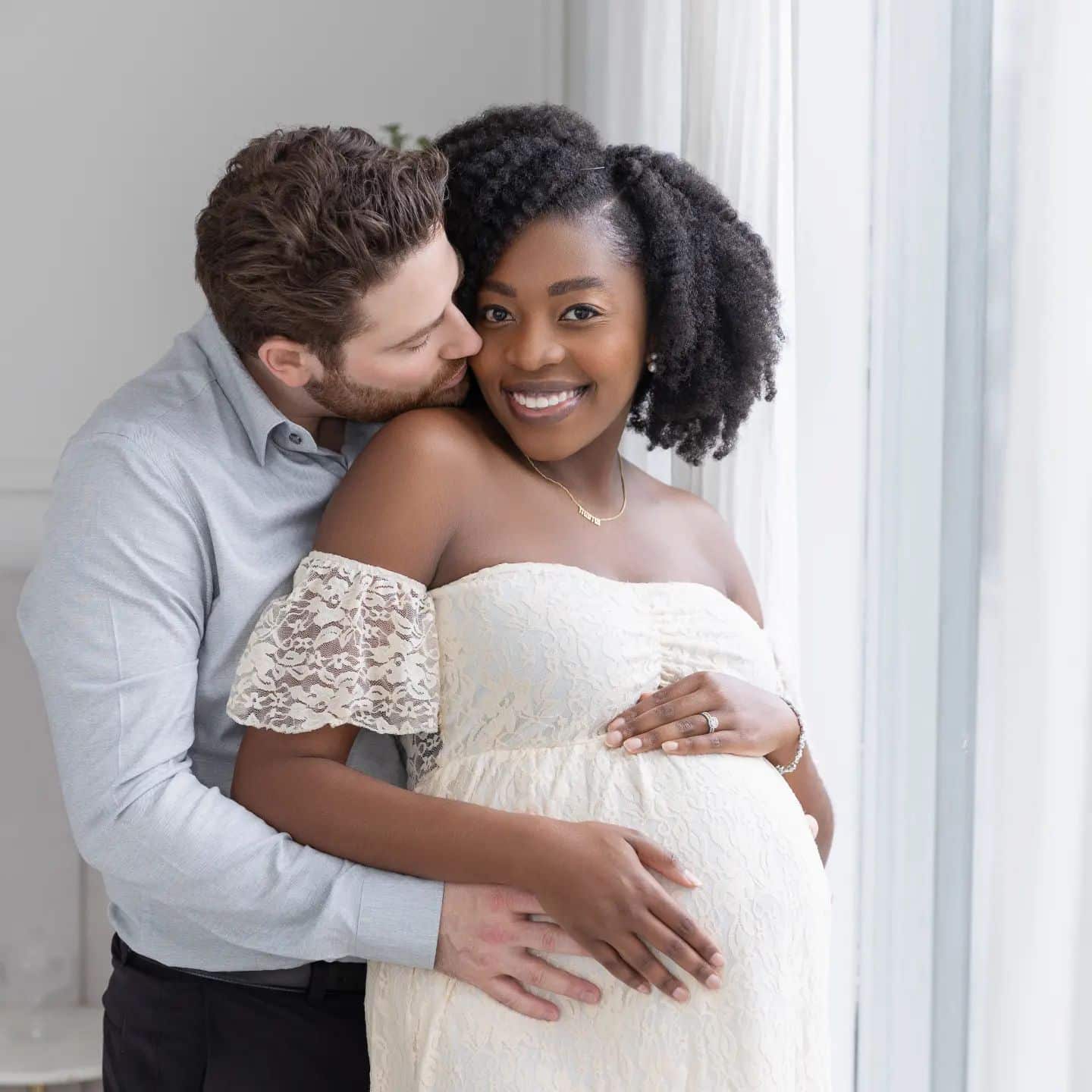 An intimate indoor maternity portrait of a man kissing his pregnant partner's shoulder, captured during a professional pregnancy photoshoot in the GTA.
