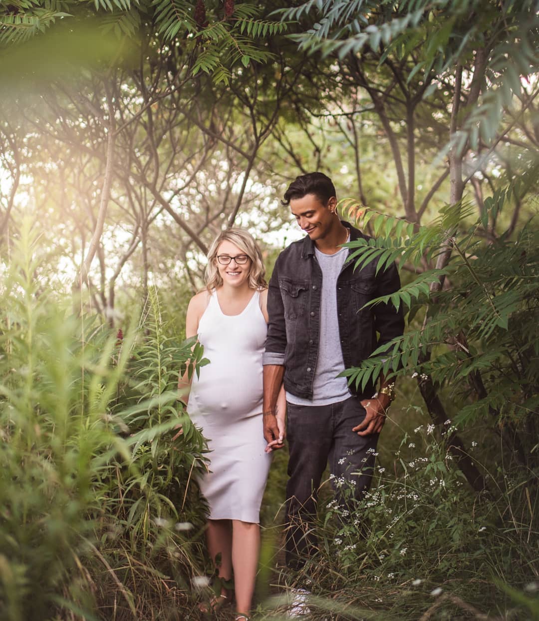 An expectant couple walking hand-in-hand through a lush forest trail during a scenic maternity photo session Mississauga.